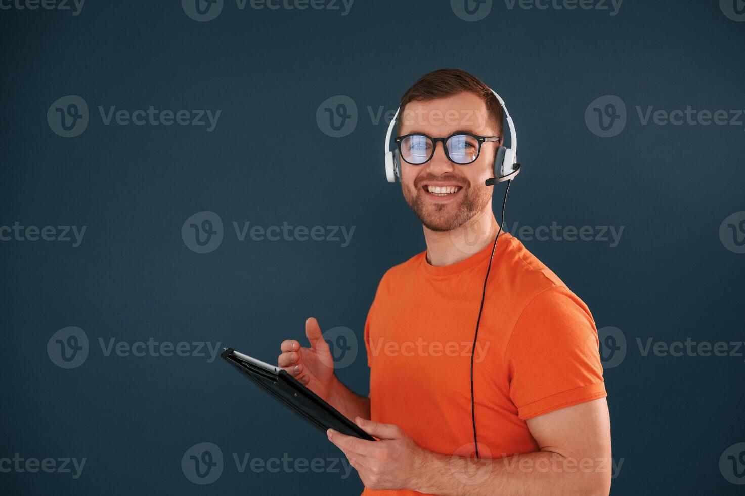 Handsome man is in the studio against blue, background, Modern laptop and digital tablet in hands photo