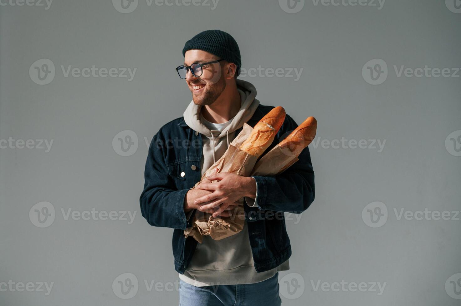 With bunch of baguettes in hands.. Handsome man is in the studio against white background photo