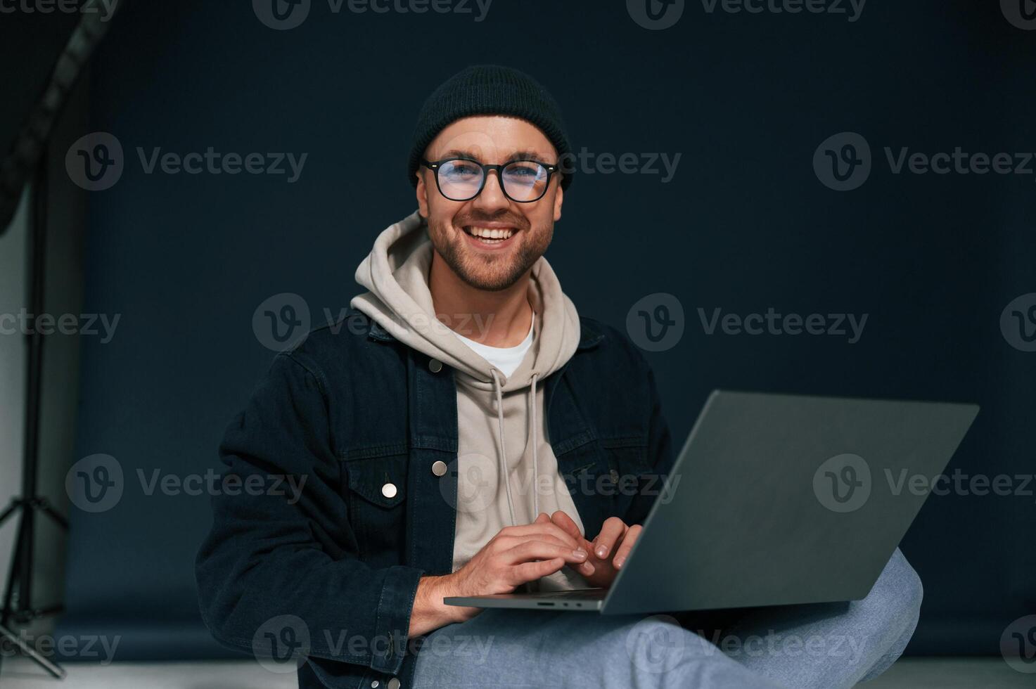 Using laptop and smiling. Handsome man ,is in the studio against background photo