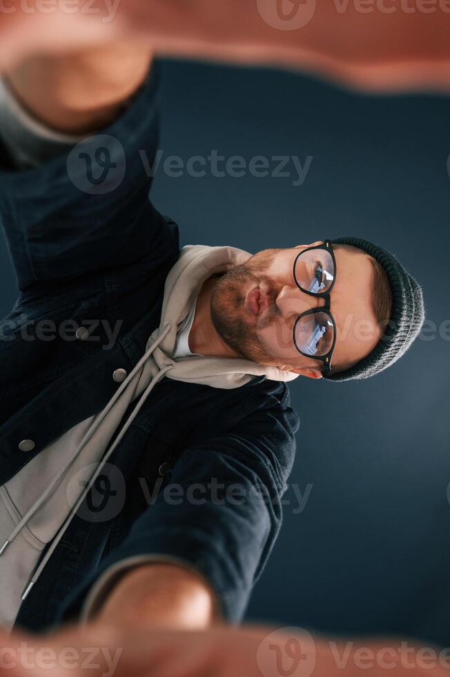 Handsome man is in the studio against, ,blue background, Making selfie photo