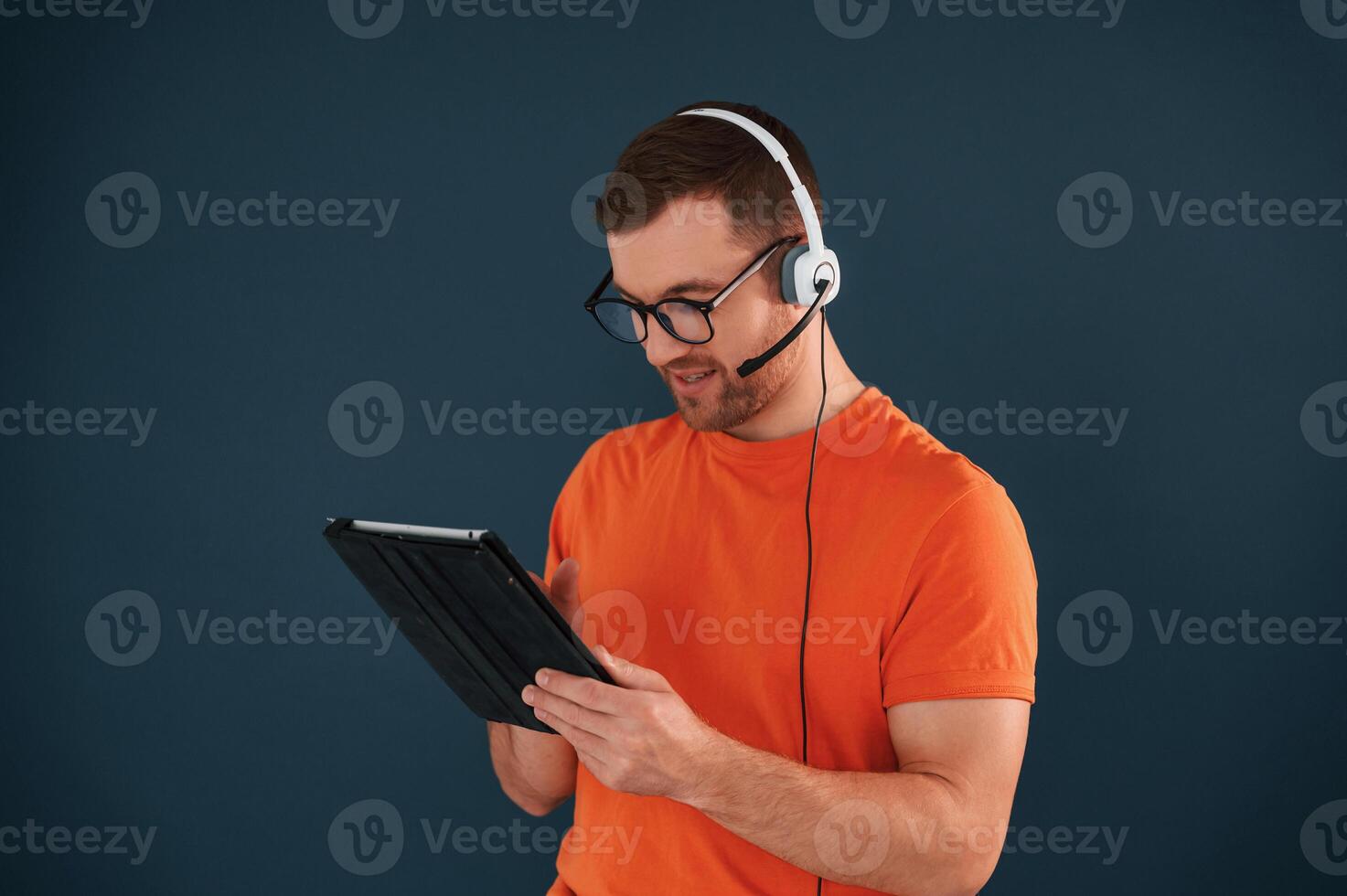 Handsome ,man is in the studio against blue background, Modern laptop and digital tablet in hands photo