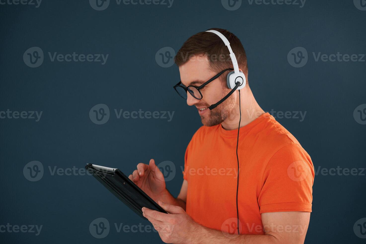 Handsome, man is in the studio against blue background, Modern laptop and digital tablet in hands photo