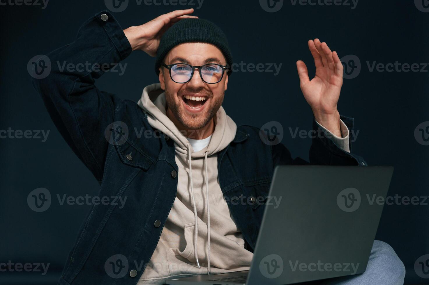 Celebrating success. Feeling uplifting. Using laptop. Handsome man is in the studio against background photo