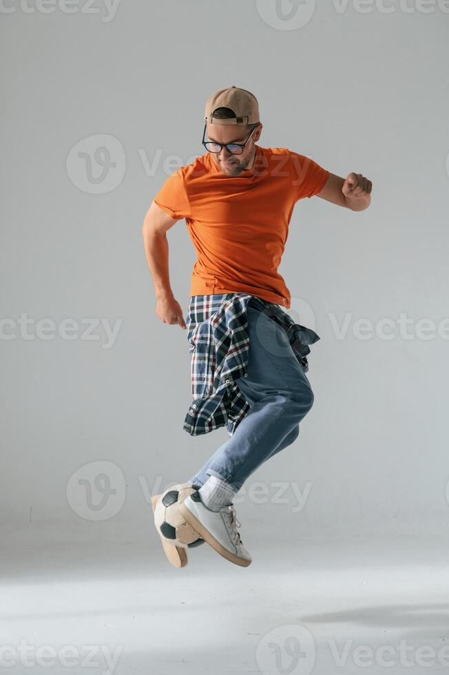 Doing tricks, playing with soccer, ball. Handsome man is in the studio against white background photo