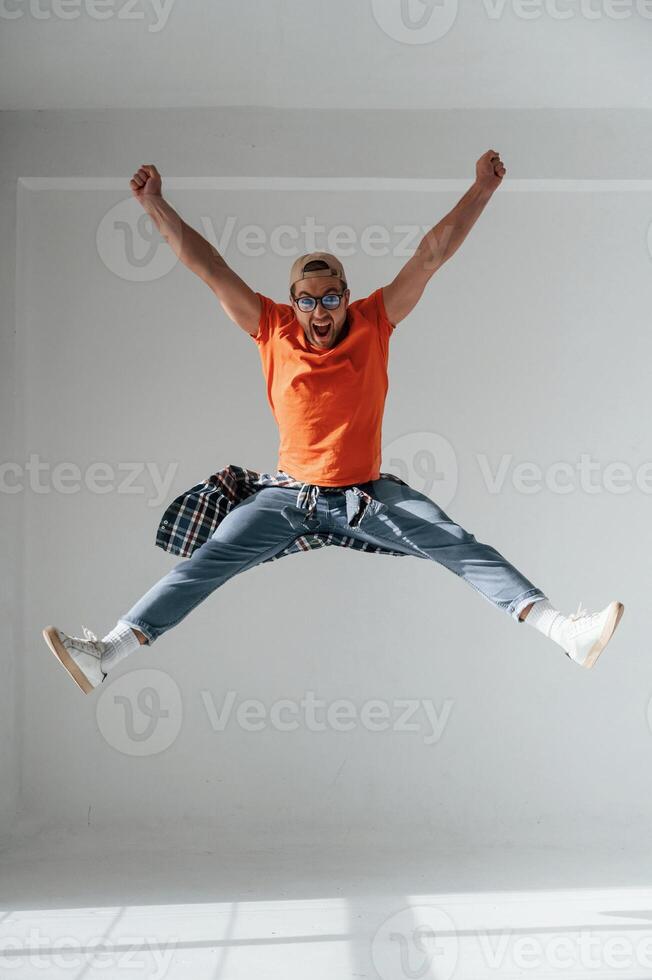 Happy guy is jumping, screaming and celebrating success. Handsome man is in the studio against white background photo