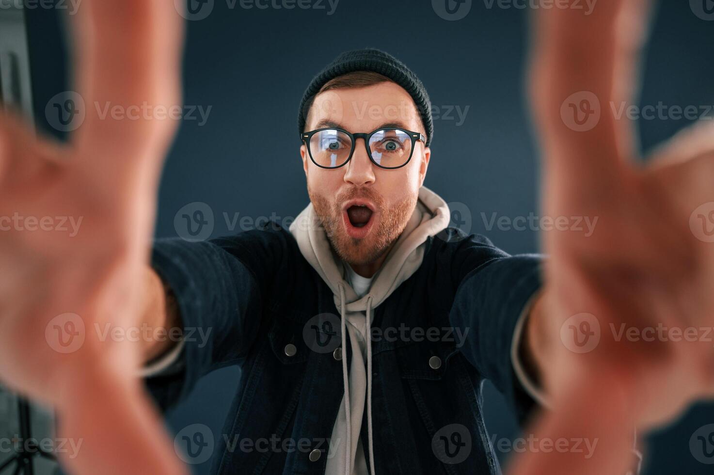 Making the ,photo by hands, pretending. Smiling. Handsome man is in the studio against blue background photo