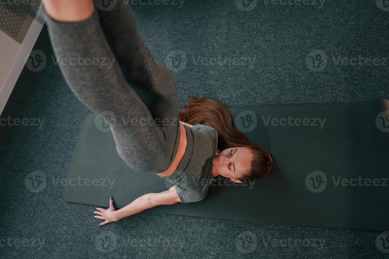 Asana, with legs up. Young woman in yoga clothes doing fitness indoors photo