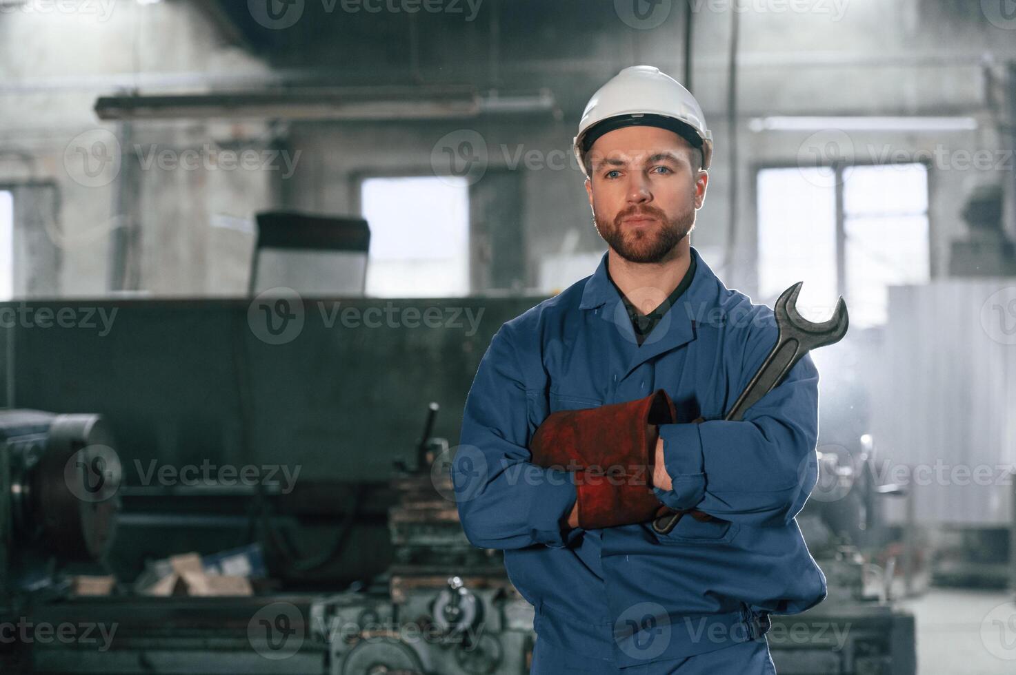 Front, view. Factory worker in blue uniform is indoors photo