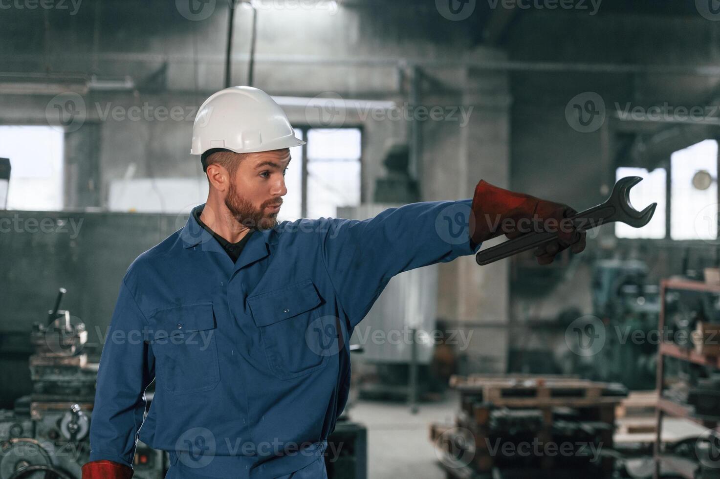 Front ,view. Factory, worker in blue uniform is indoors photo