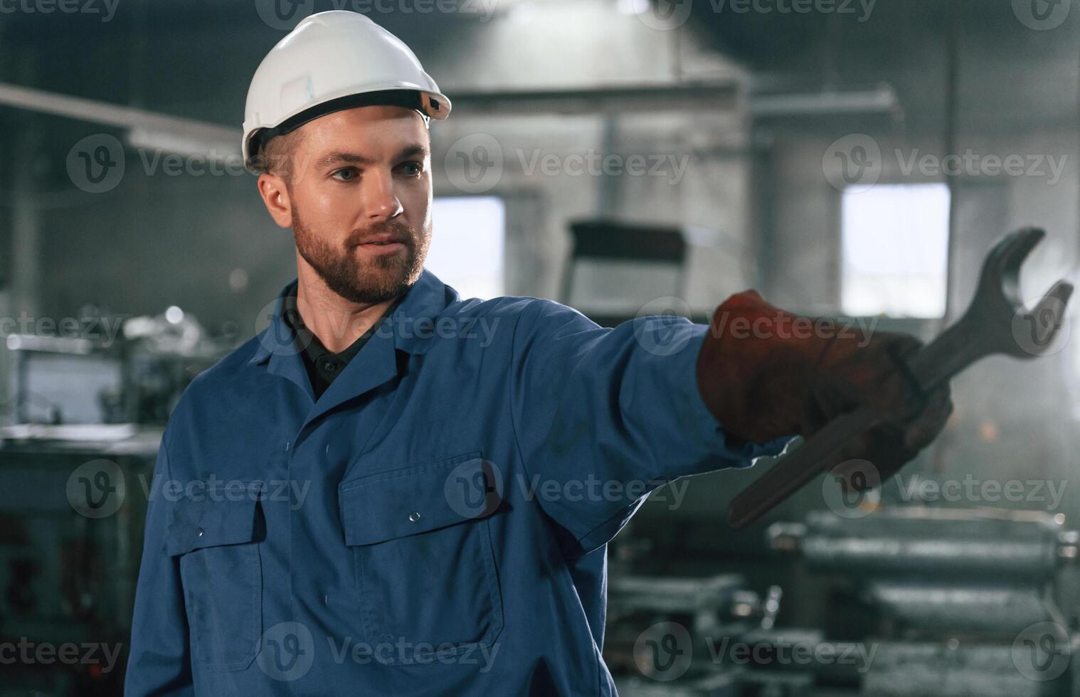 Front view.. Factory ,worker in blue uniform is indoors photo