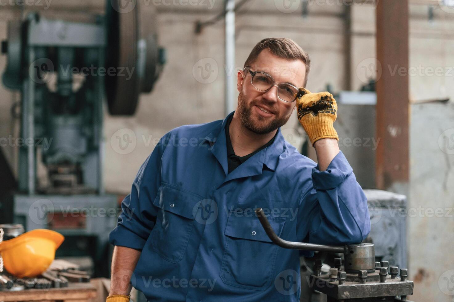 Front view. Factory ,worke,r in blue uniform is indoors photo