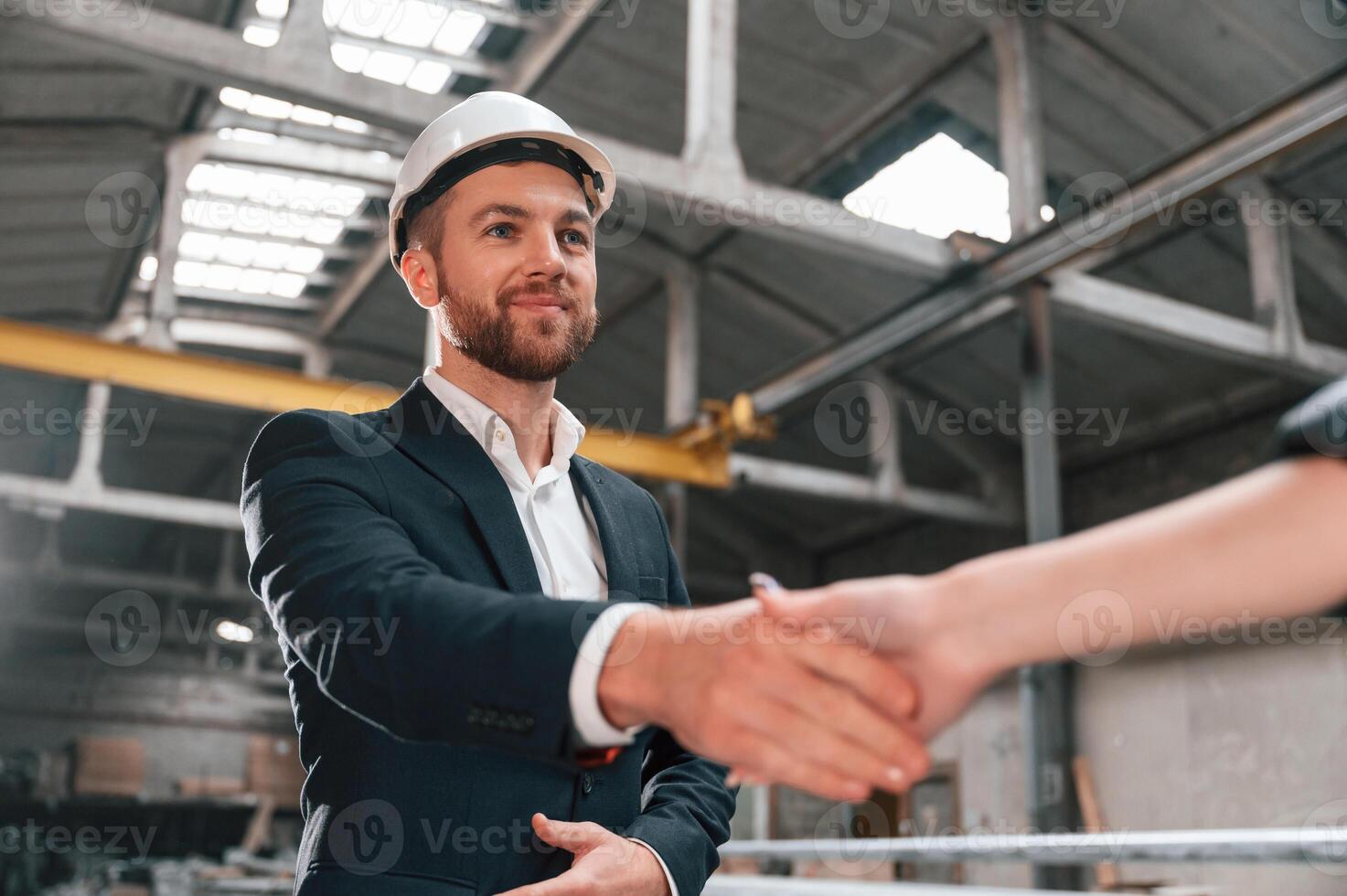 Handshake with partner.. Manager in black formal wear at the factory photo