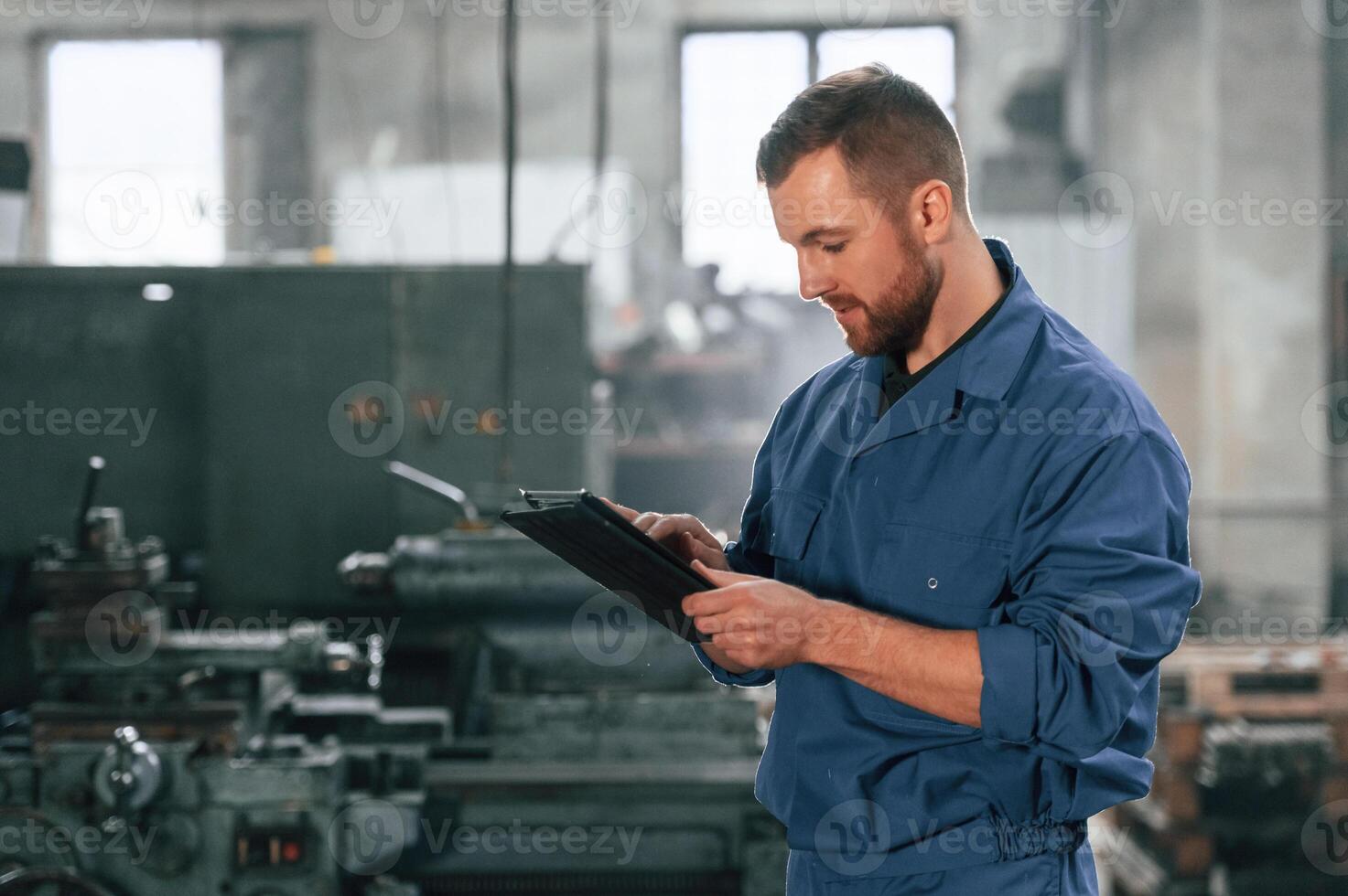 Front ,view. Factory worker in blue uniform is indoors photo