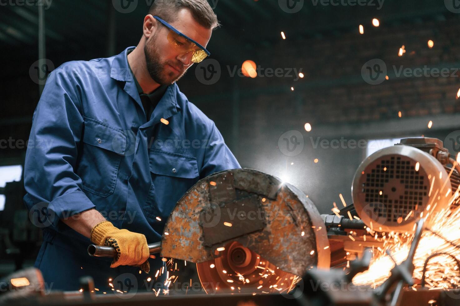Many, of the sparks. Welding the metal. Factory worker in blue uniform is indoors photo