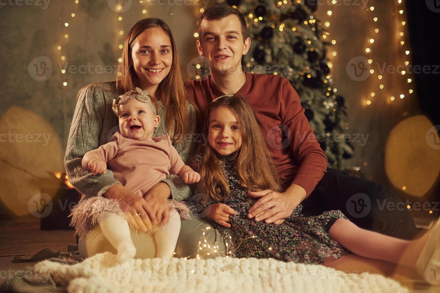 Happy, family is sitting indoors, celebrating new year. With two little kids photo