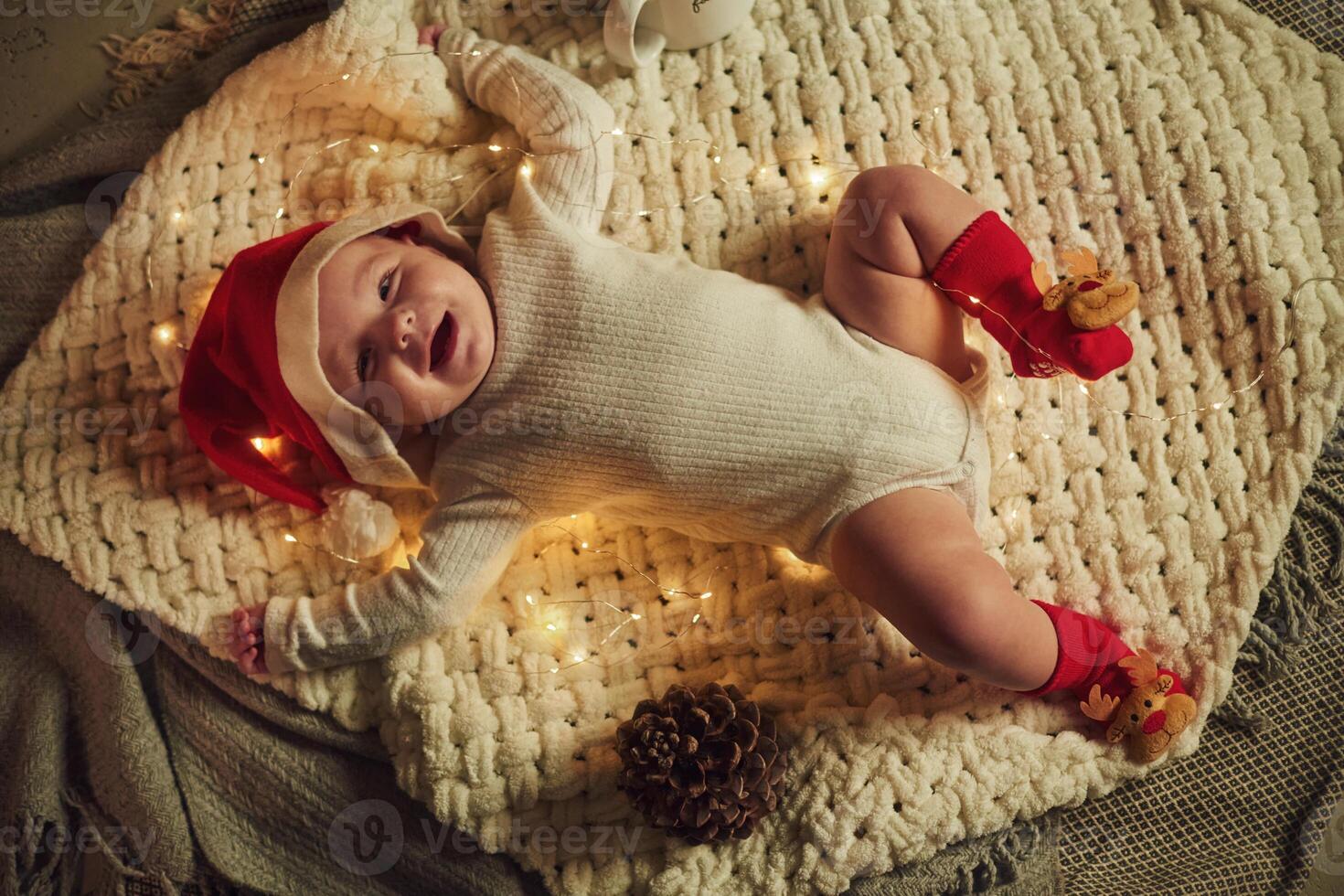 Little ,baby is lying down, on the ground. In Christmas clothes. Conception of new year photo