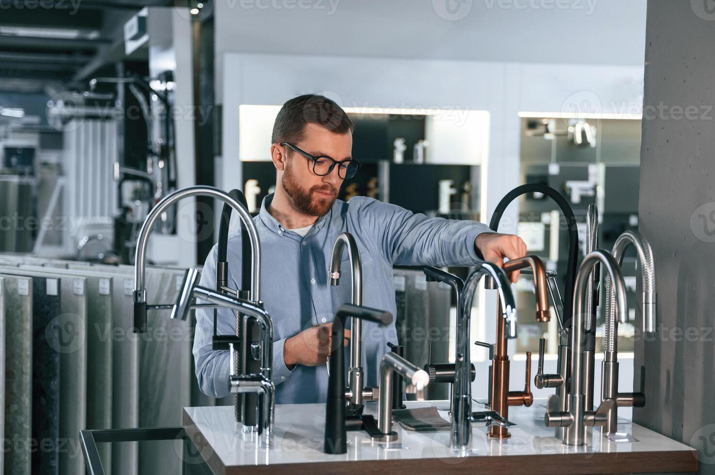A ,large, selection ,of water faucets. Man chooses a products in a sanitary ware store photo