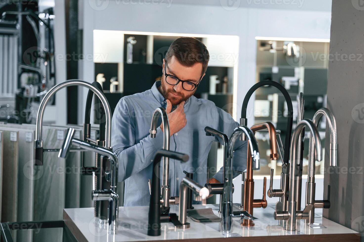 A ,large, selection of ,water faucets. Man chooses a products in a sanitary ware store photo