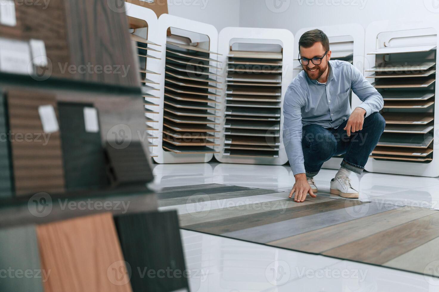 Sitting and, choosing parquet. Man is in the store of goods for the home photo