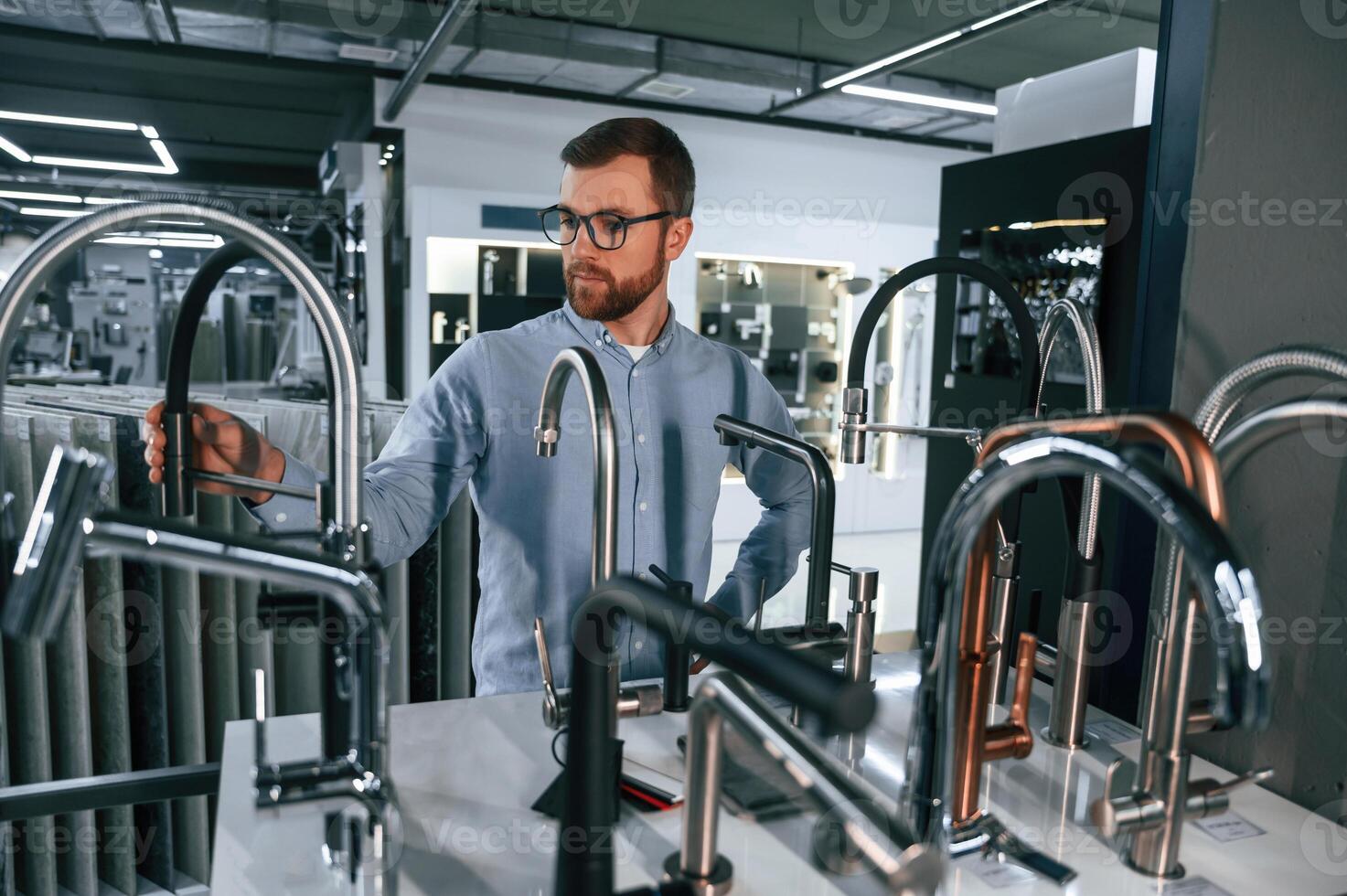 A large, selection of water faucets. Man chooses a products in a sanitary ware store photo