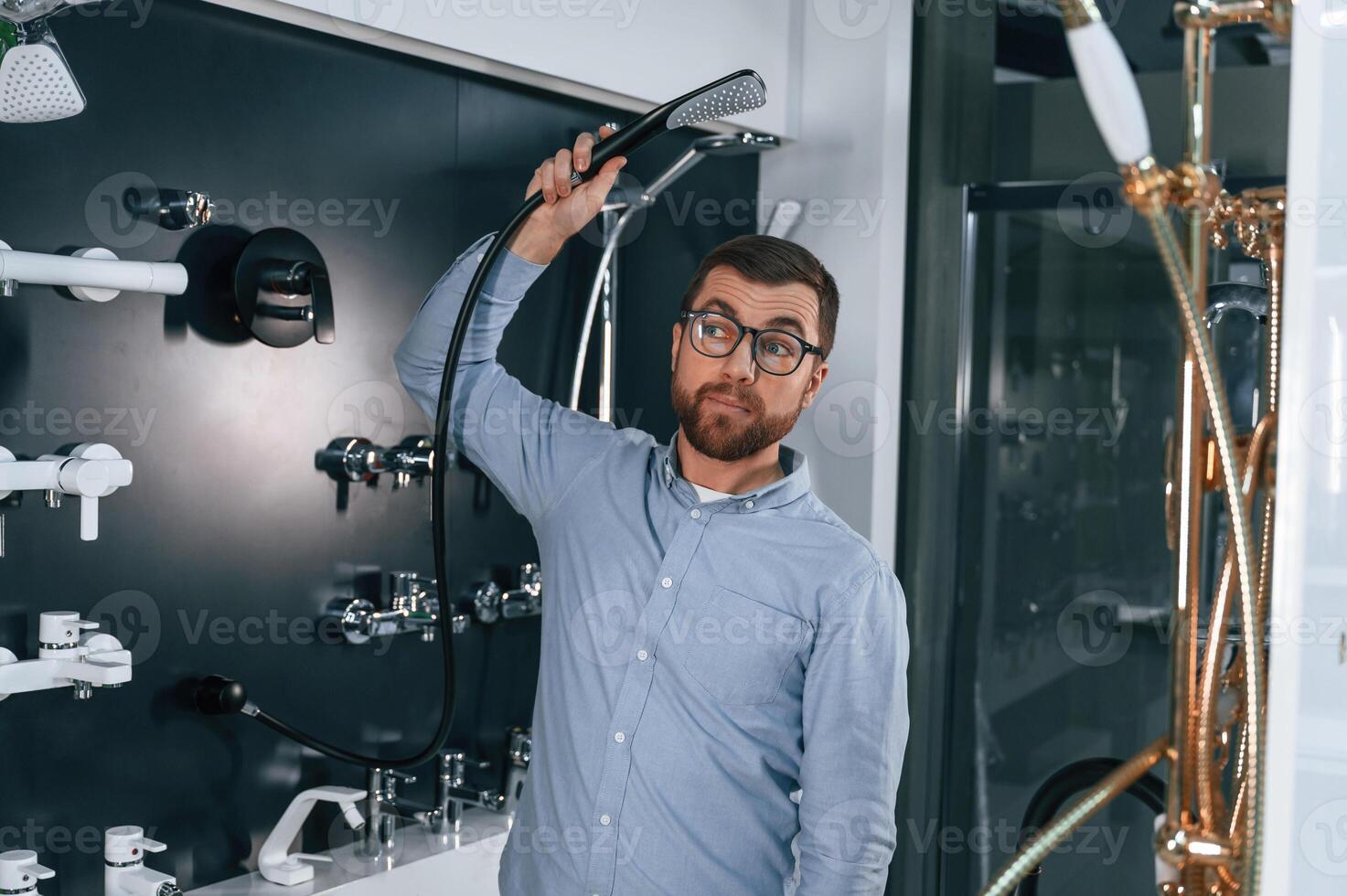 Playin,g with shower, faucet. Man chooses a products in a sanitary ware store photo