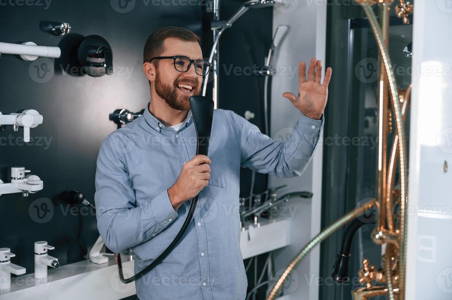 Playing with shower faucet, singing. Man chooses a products in a sanitary ware store photo