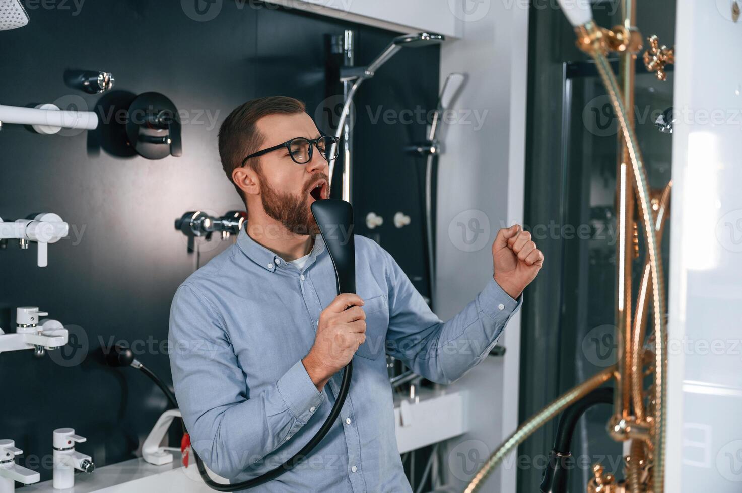 Playing with shower faucet,, singing. .Man chooses a products in a sanitary ware store photo