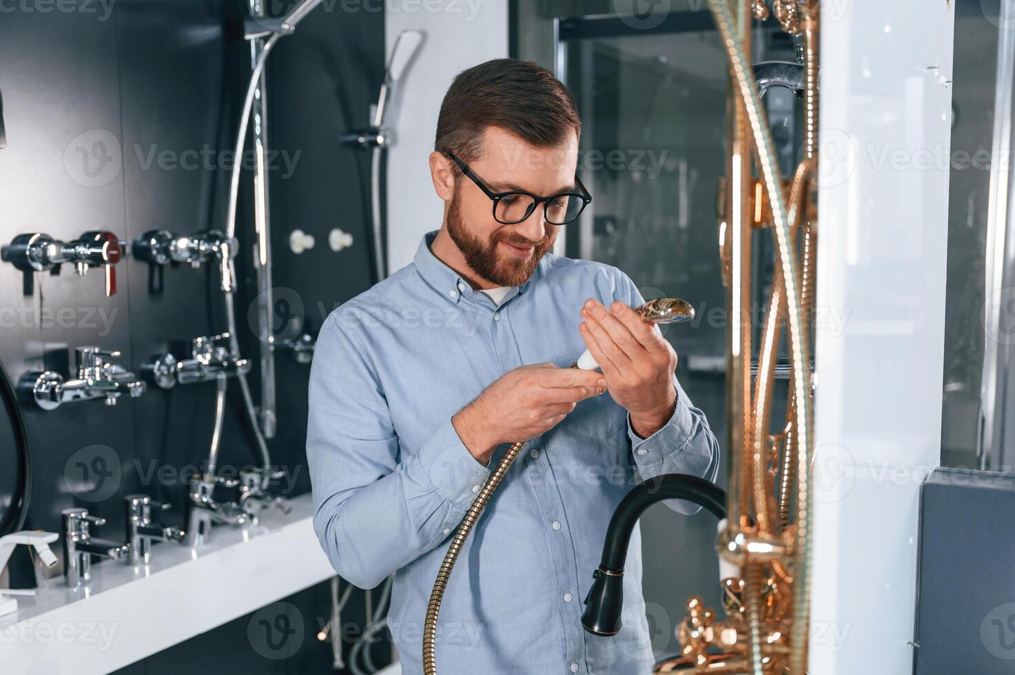 Selects a shower faucet.. Man chooses a products in a sanitary ware store photo