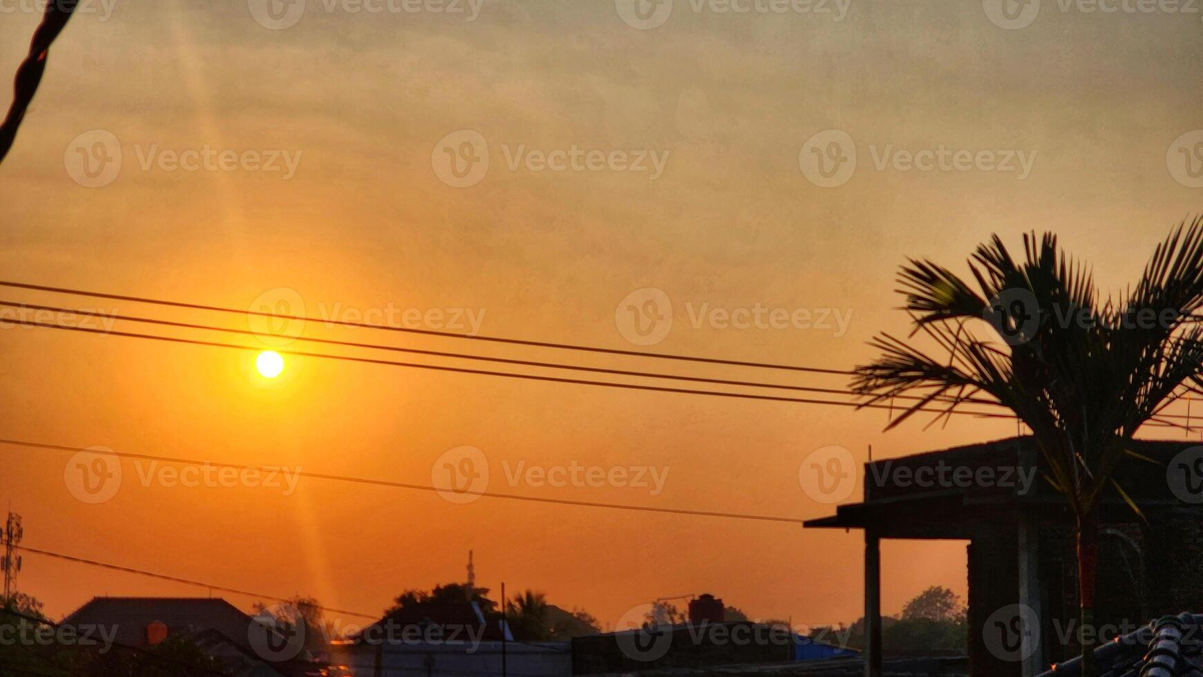the sun is setting over a village with palm trees photo