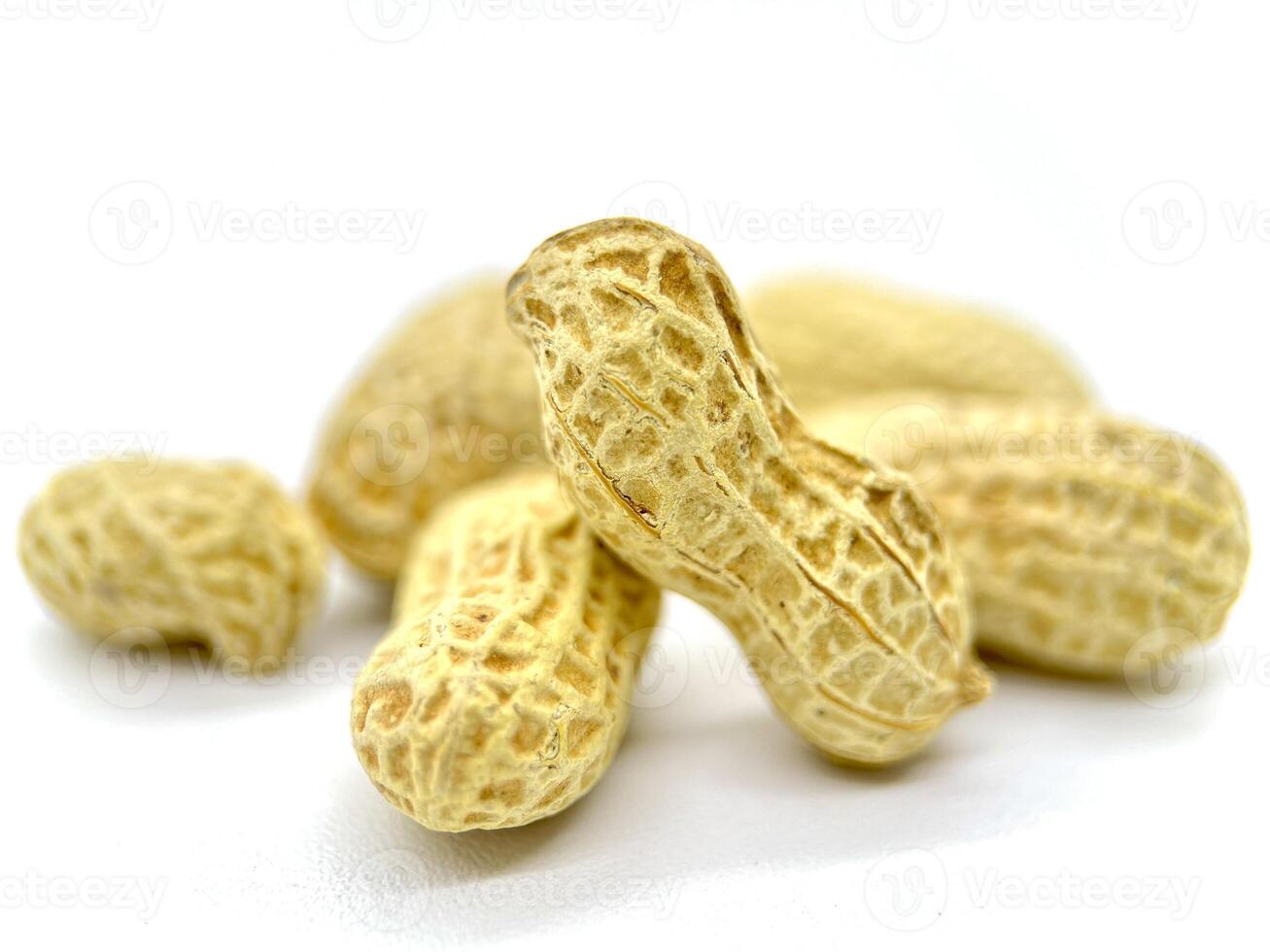 There is a sizable pile of peanuts still inside their shells, beautifully arranged on a white background for a clean and simple presentation photo