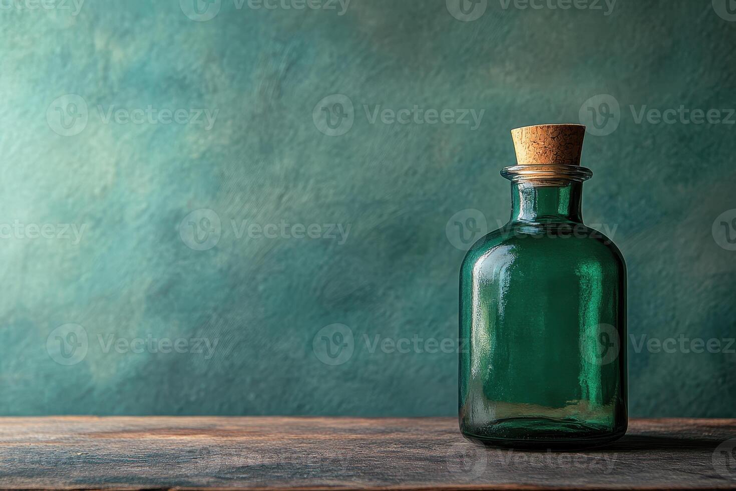 Green Glass Bottle with Cork Stopper on Wooden Surface Against a Teal Background photo