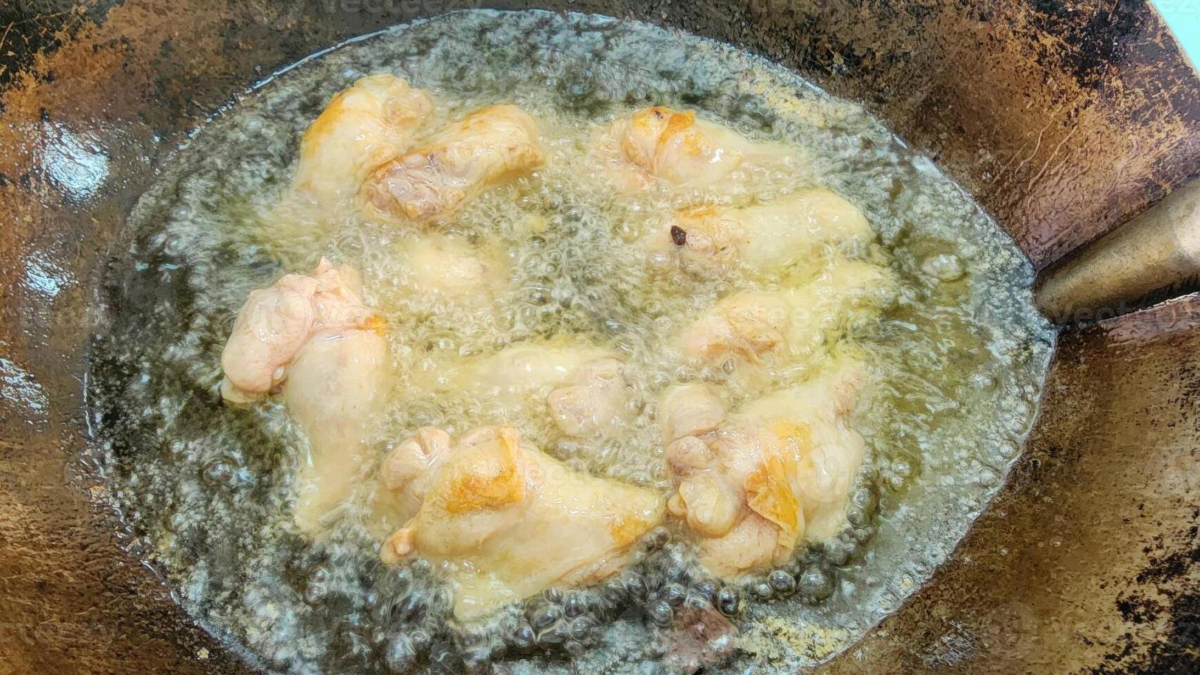 Sizzling Chicken Wings Frying in Hot Oil on a Wok photo