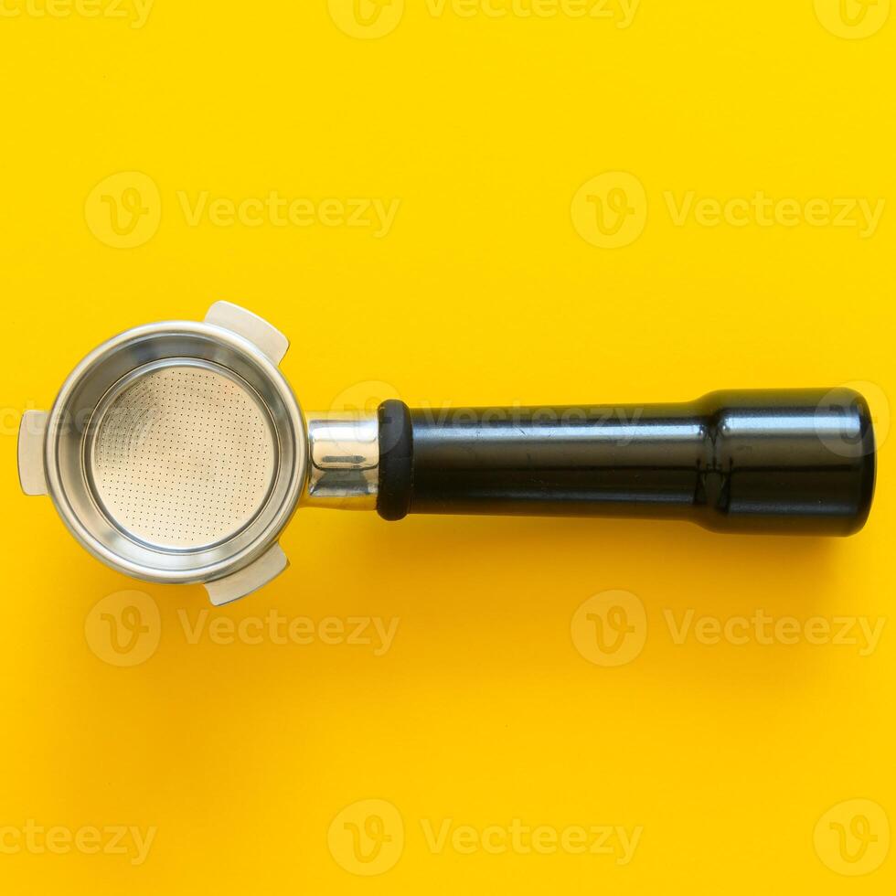 Empty espresso portafilter on a yellow colored background photo