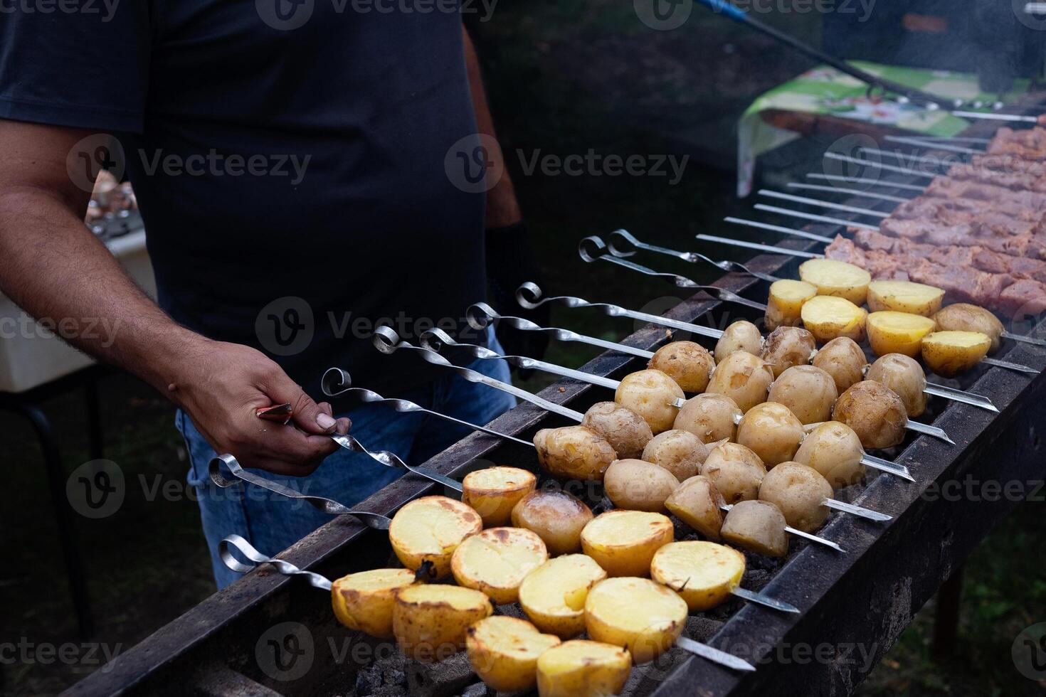 Cooking shashlik on a metal skewer and grilled vegetables. Grilled meat and vegetables. Delicious street food. photo