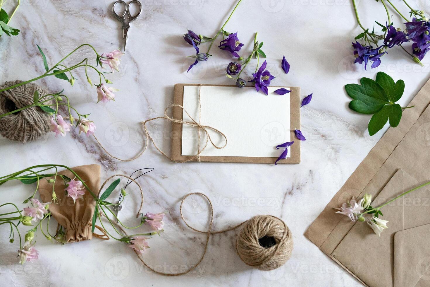 Marble desk with pink and blue flowers, postcard, kraft envelope, twine, cotton branch. Layout of Women's Day or Mother's Day, St. Valentine's Day, flat position, top view. photo