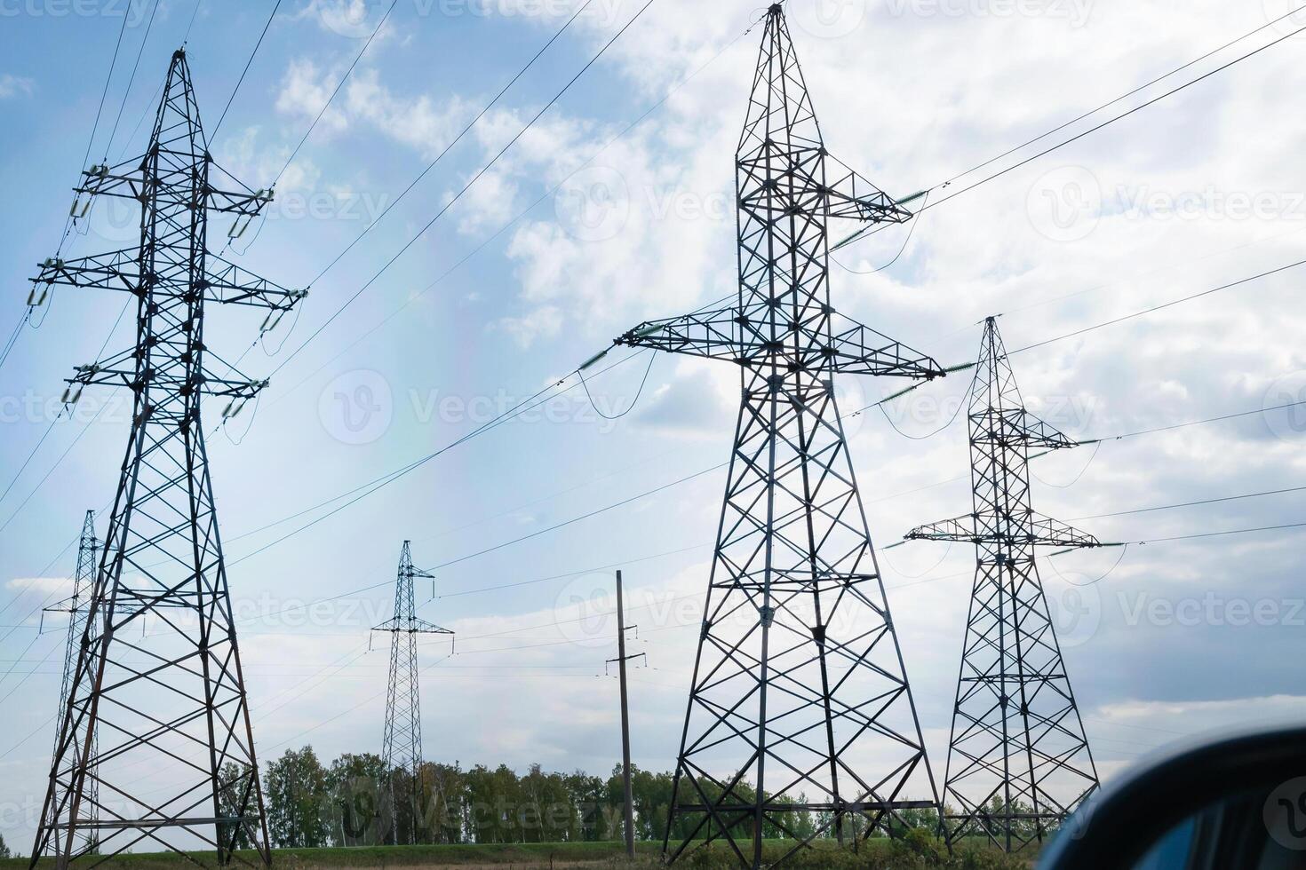 power pylons in a flat and green agricultural landscape on a sunny day with cirrus clouds in the blue sky. photo