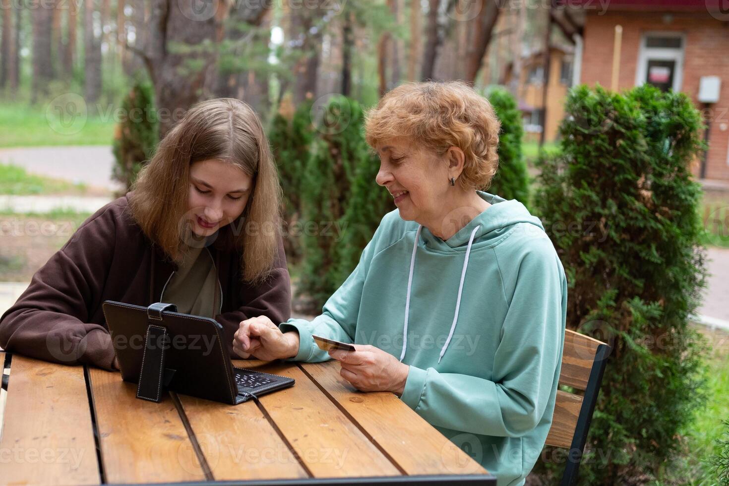 Generational connection a grandmother and granddaughter working together on a tablet outdoors. photo