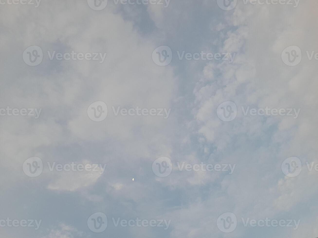 A soft, cloudy sky with gentle shades of blue and white, creating a peaceful and dreamy atmosphere. The clouds spread across the sky in a delicate, airy pattern. photo