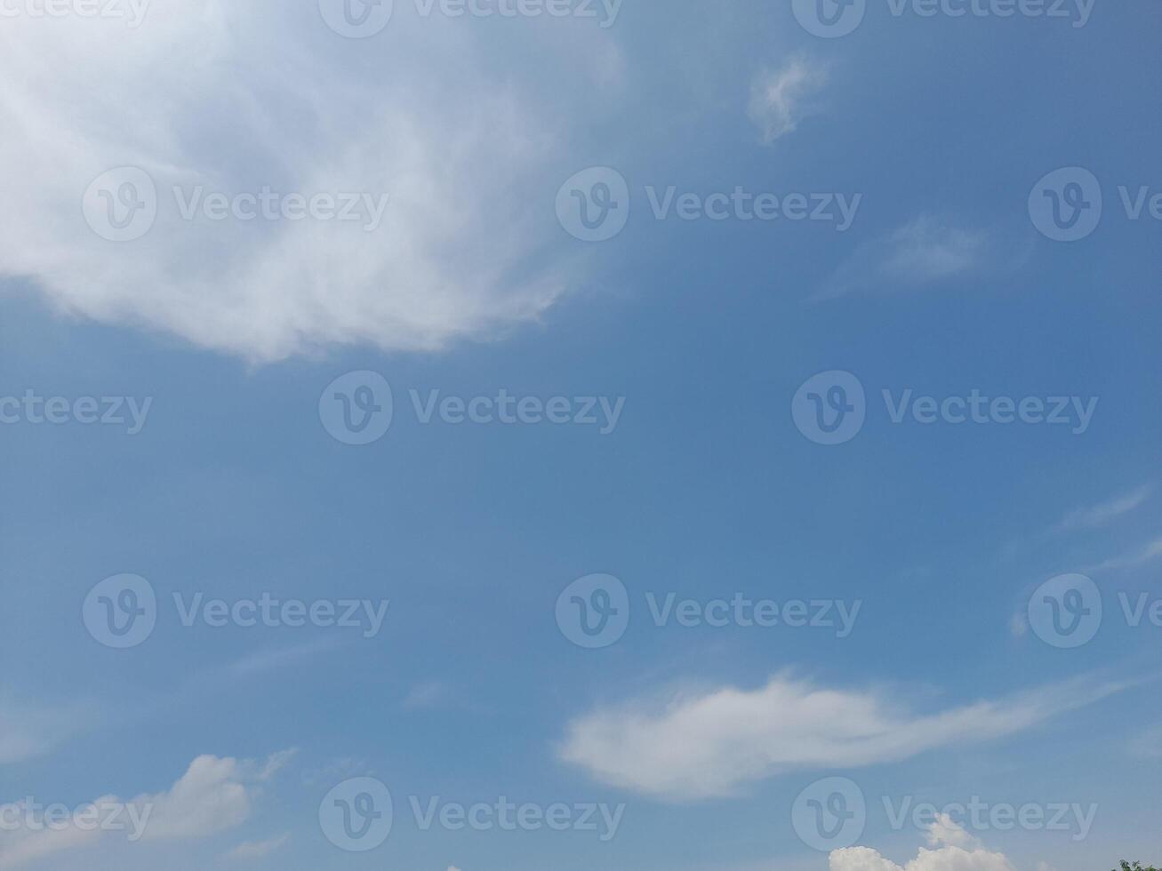 A bright blue sky with soft, wispy white clouds scattered across, creating a serene and peaceful atmosphere. photo