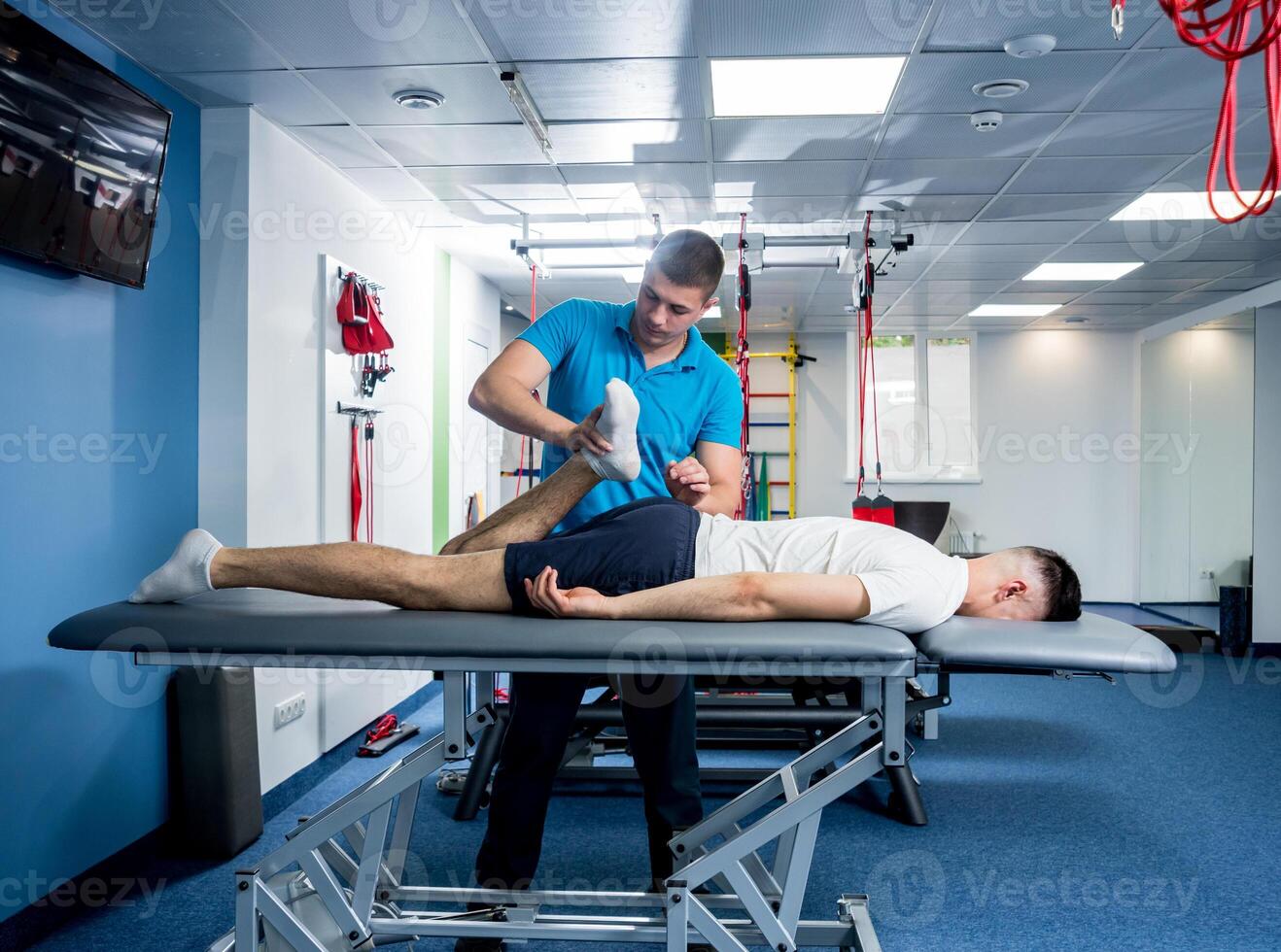 Rehabilitation therapy. Physiotherapist working with young male patient photo