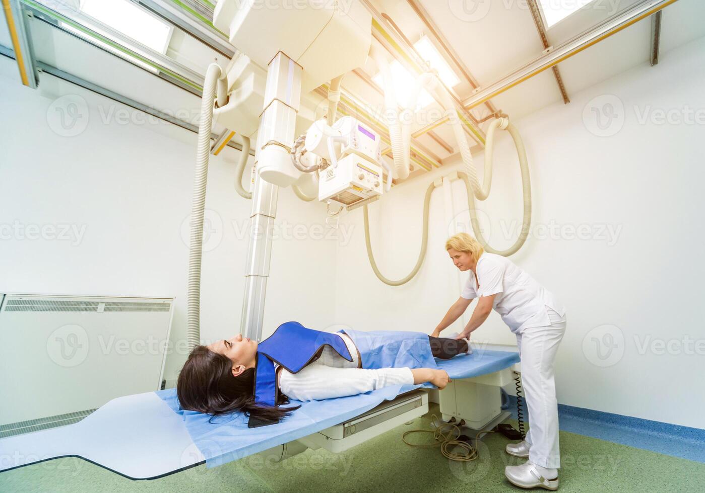 Radiologist and patient in a x-ray room. Classic ceiling-mounted x-ray system. photo