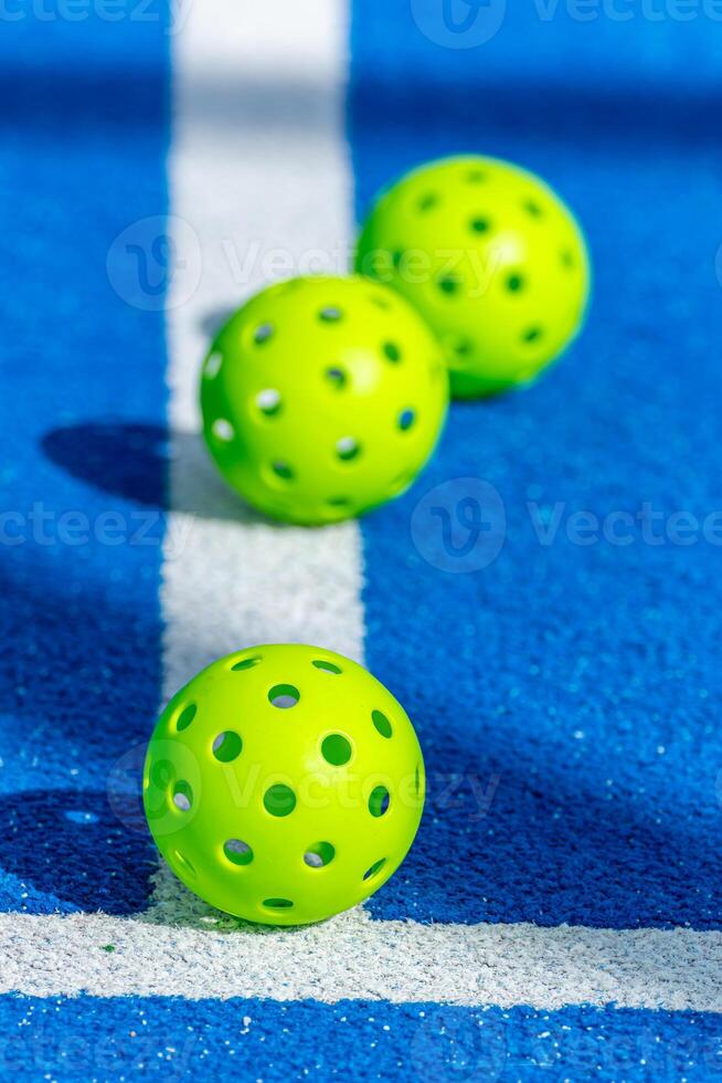 three pickleball balls on the line in a blue court, racket sports concept background photo