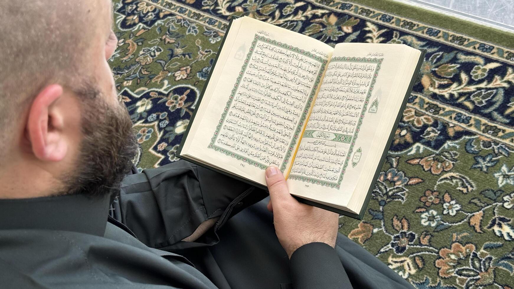 Mecca, Saudi Arabia - May 2, 2024. Young man, Hajj and Umrah pilgrim sitting and reading Quran in Masjidil Haram, Great Mosque in Makkah, Saudi Arabia. Hajj 2024. photo