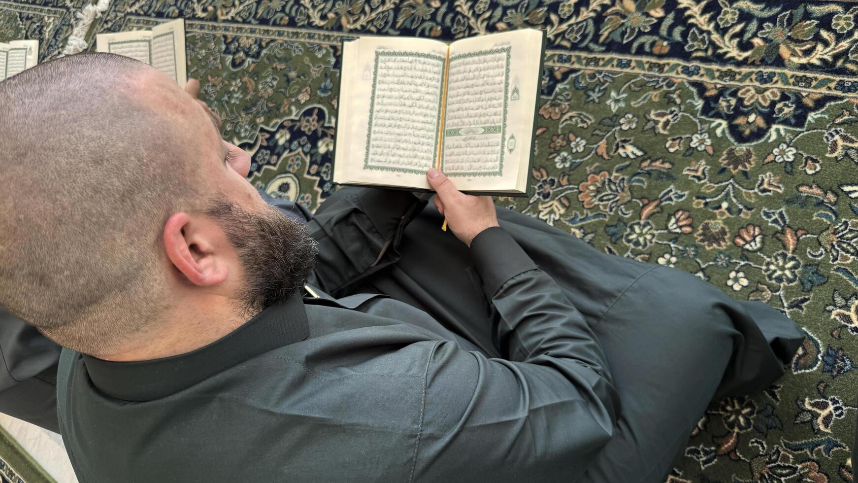 Mecca, Saudi Arabia - May 2, 2024. Young man, Hajj and Umrah pilgrim sitting and reading Quran in Masjidil Haram, Great Mosque in Makkah, Saudi Arabia. Hajj 2024. photo