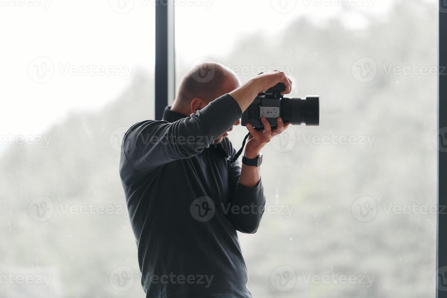 A professional photographer is captured working in his studio by a window, skillfully capturing a business photoshoot with precision and creativity. photo