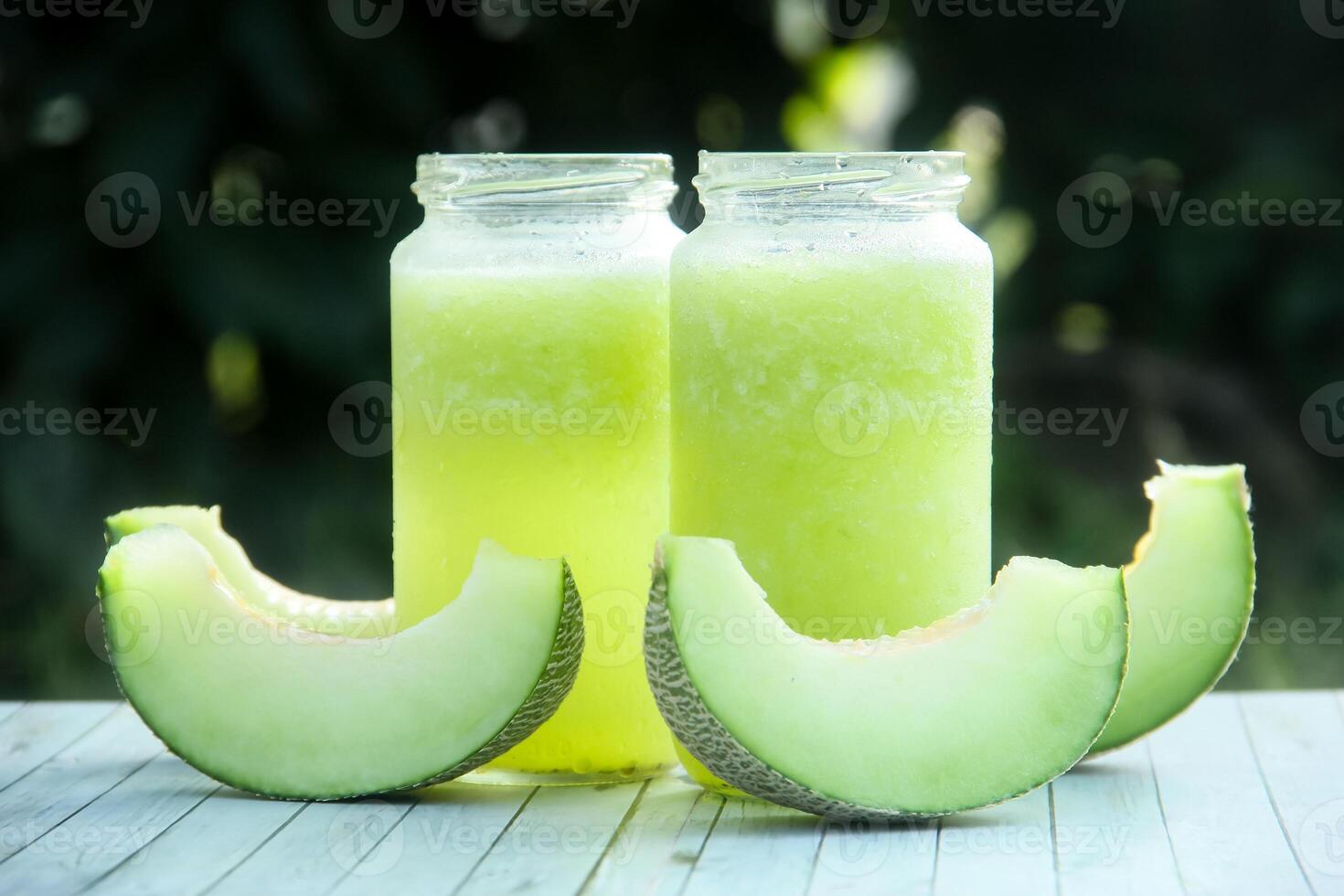 Two glass jars with green juice and slices of melon photo
