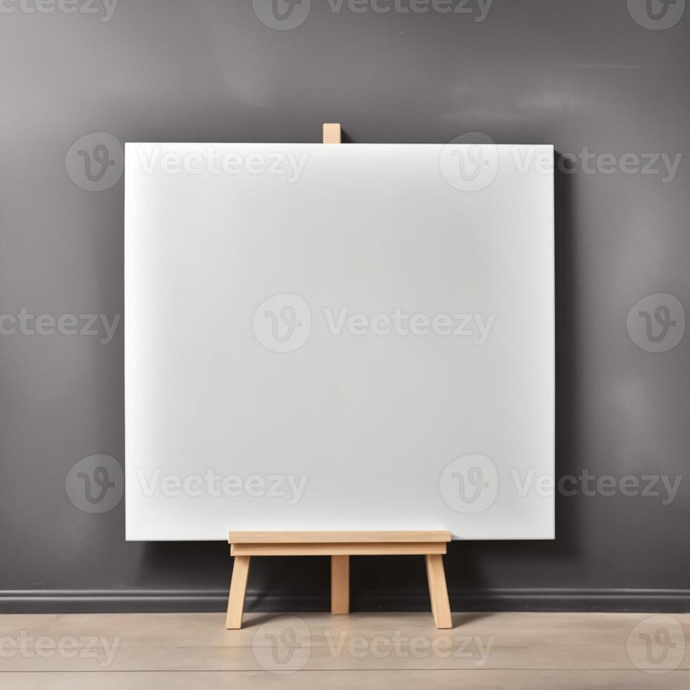 Blank canvas on easel in empty room with gray wall photo