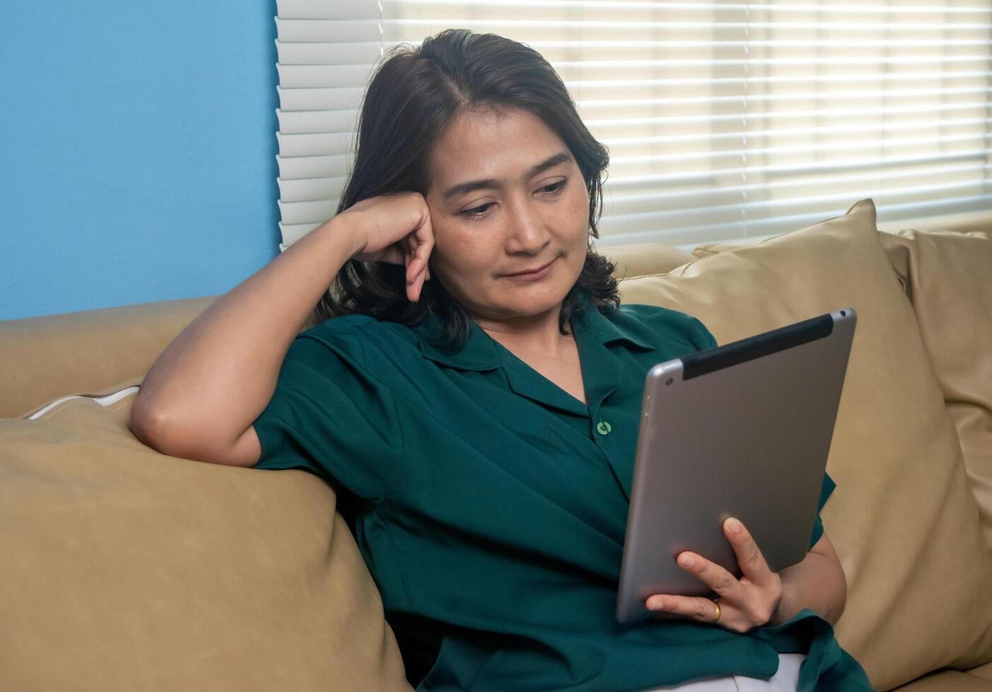 Asian women sitting on sofa holding digital tablet using social media watching movie online ,relaxing on vacation ,lifestyles concepts at home photo