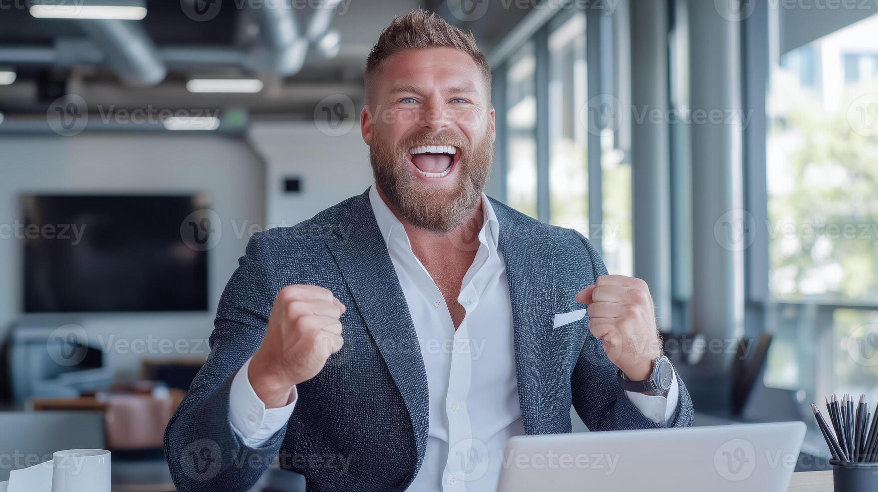 Satisfied businessman in a suit exults in front of a laptop in a modern office. photo