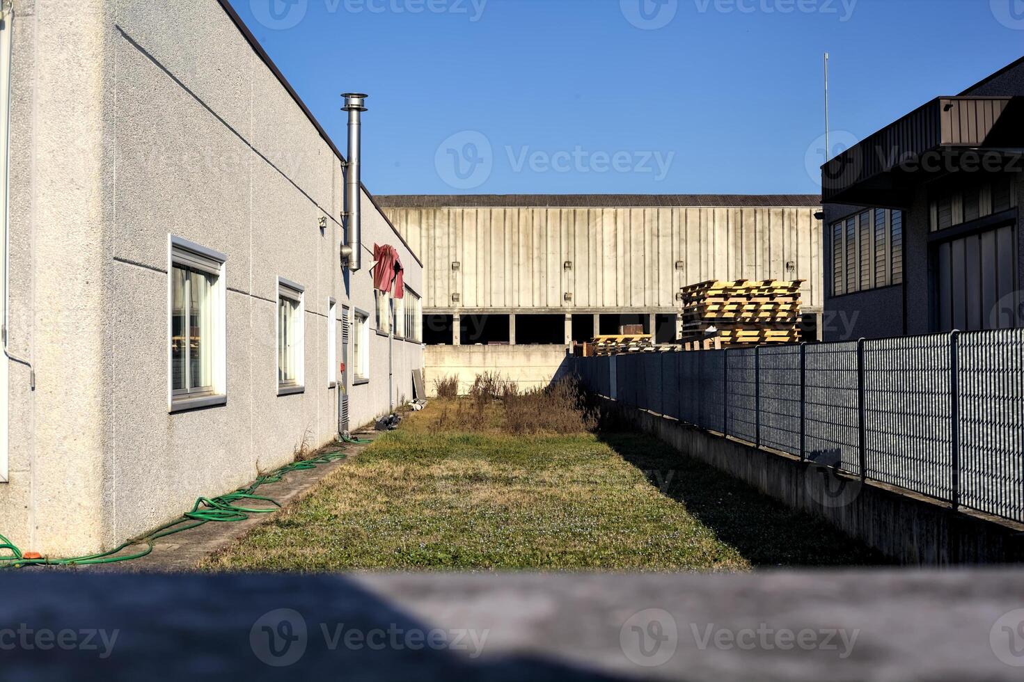Strip of a garden between buildings with an abandoned warehouse in the background photo